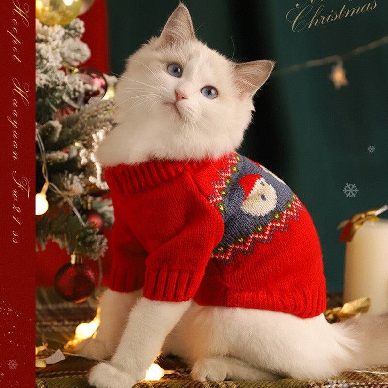 Cat wearing a red Christmas sweater by a decorated tree, showcasing festive pet clothing.