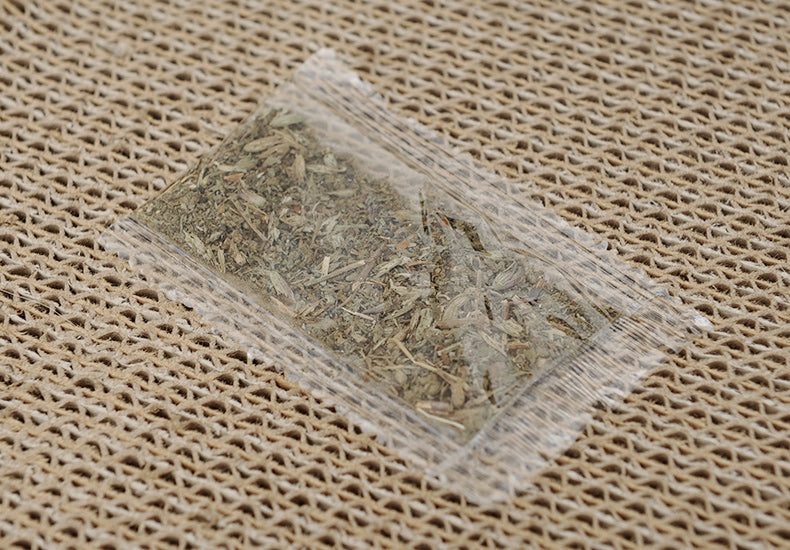 Durable cat scratching lounger with catnip packet on textured surface.