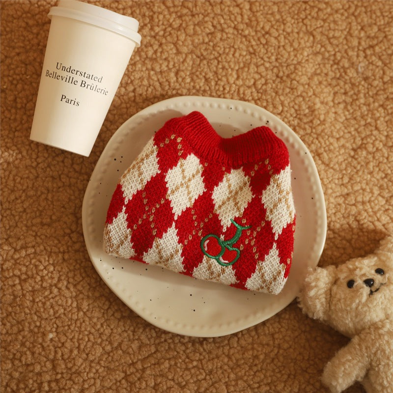 New Year cat clothing in red and white checkered pattern on a table with coffee and teddy bear.