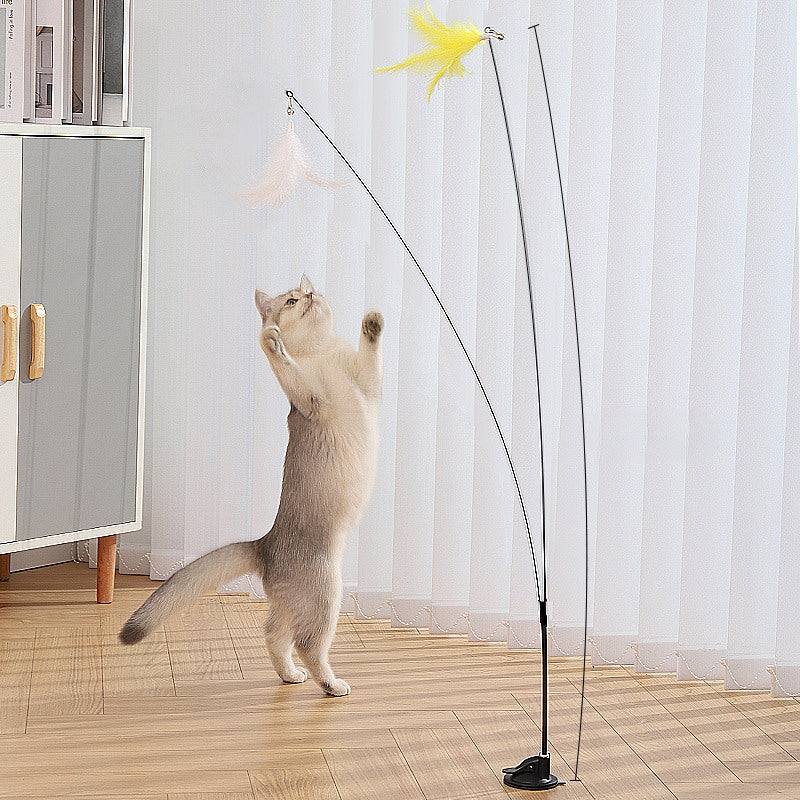 Cat playing with a steel wire teaser featuring a feathered toy, supported by a suction cup base for self-amusement.